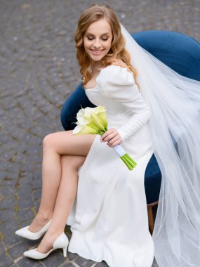 Güzel gelin bir sandalyede oturuyor ve kalenin arka planında poz veriyor.