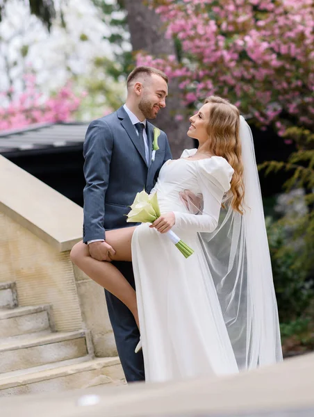 Bonito casal caucasiano recém-casado abraçando no fundo da sakura — Fotografia de Stock