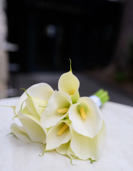 Beautiful wedding bouquet of white calla lilies on a white table — Stock fotografie