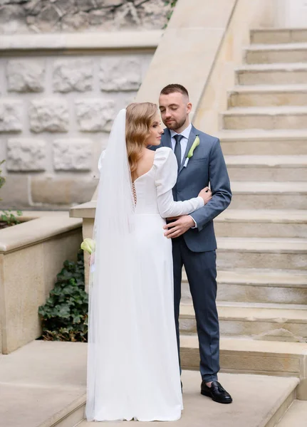 Beautiful caucasian newlywed couple posing on the background of an ancient house — Stockfoto