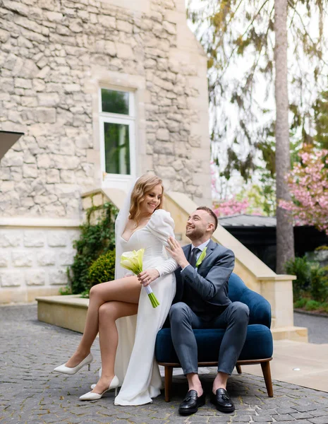 Beautiful wedding couple sitting on chair on the background of an ancient house — Stockfoto