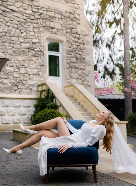 Güzel gelin bir sandalyede oturuyor ve kalenin arka planında poz veriyor.