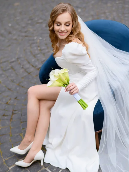 Güzel gelin bir sandalyede oturuyor ve kalenin arka planında poz veriyor.