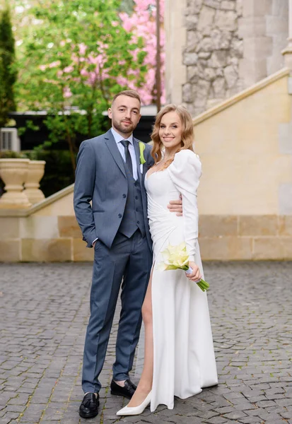Beautiful caucasian newlywed couple posing on the background of an ancient house — Stok Foto