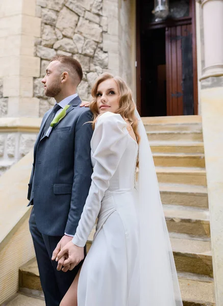 Beautiful caucasian newlywed couple posing on the background of an ancient house — Stockfoto