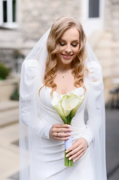 Beautiful blonde caucasian bride in a white dress posing — Stok fotoğraf