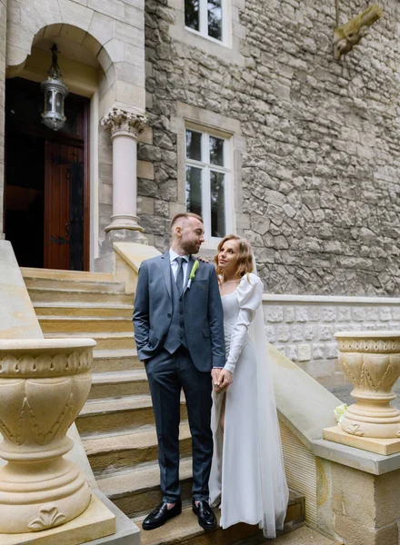 Beautiful caucasian newlywed couple posing on the background of an ancient house — Stockfoto