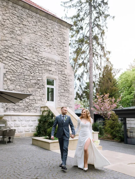 Beautiful caucasian newlywed couple posing on the background of an ancient house — Stockfoto