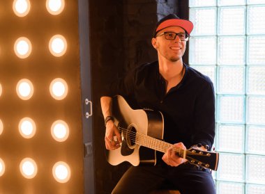 Akustik gitar çalan yakışıklı genç adam.