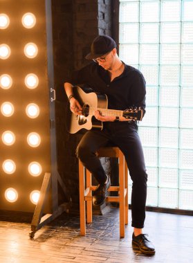 Akustik gitar çalan yakışıklı genç adam.