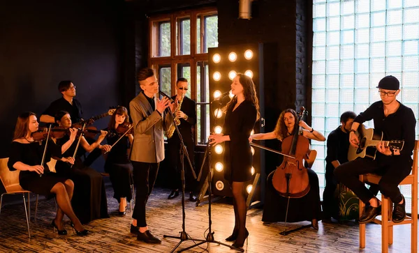 Music band with string quartet on the background of the loft interior