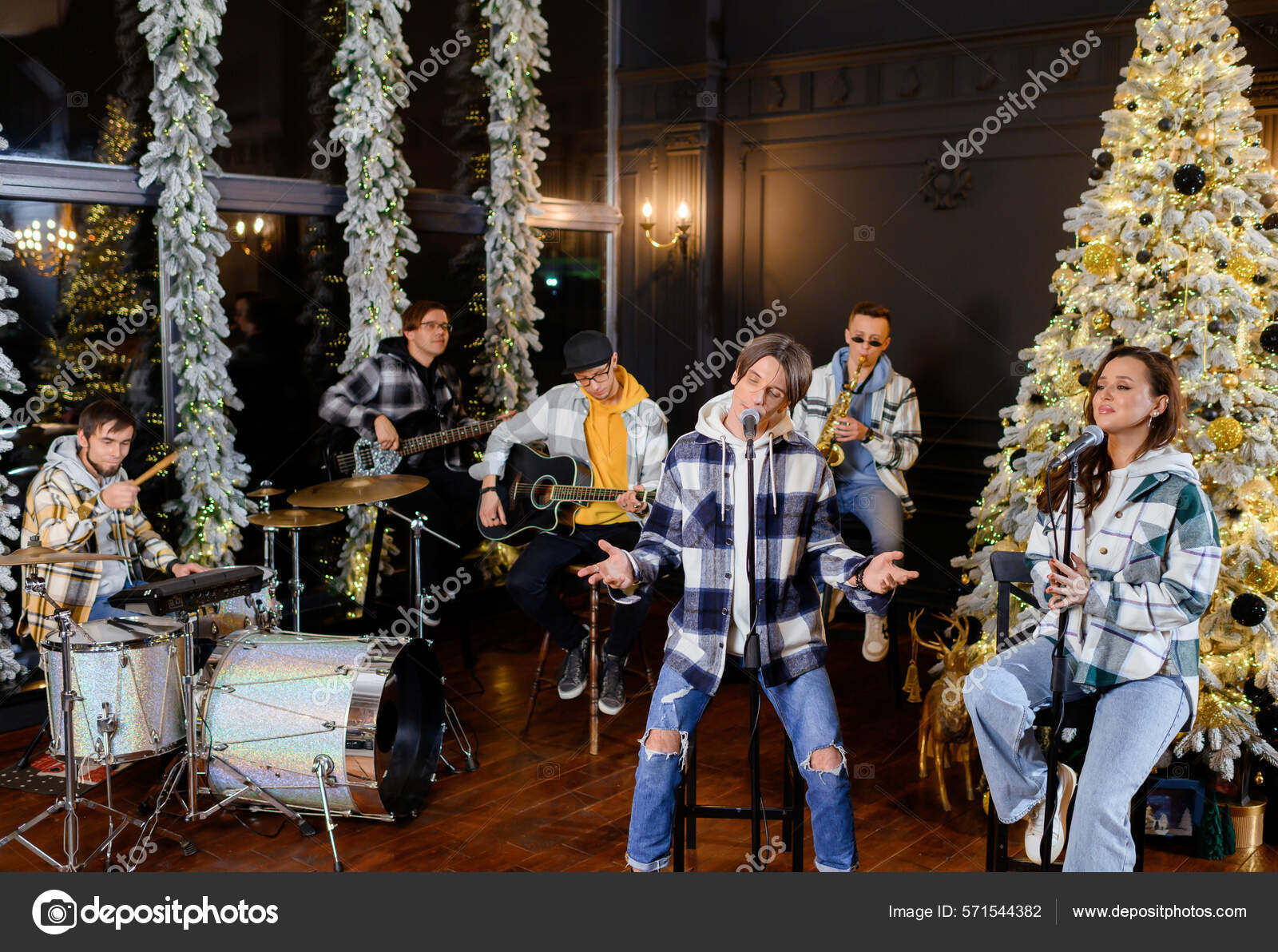 Молодая Рок-Группа Поет И Играет На Фоне Елки Стоковое Фото.