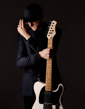 Kafkasyalı bir adam elektro gitar tutuyor.