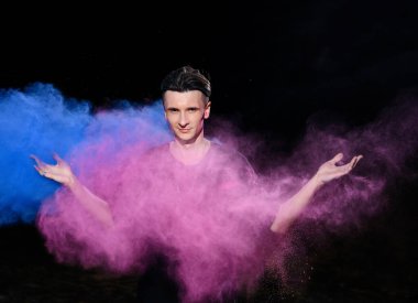 Kafkasyalı genç bir adam Holi boyalarıyla dolu duruyor. 