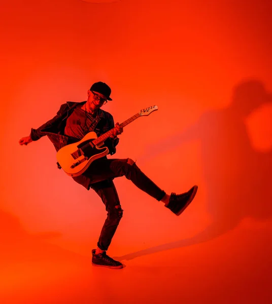 A young guitarist plays the electric guitar and jumps on a red light