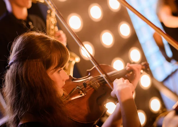 Красивая молодая скрипачка на фоне струнного оркестра — стоковое фото