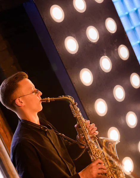 Young saxophone playing the saxophone on a loft interior