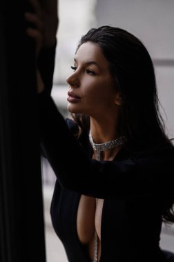 Siyah uzun saçlı, siyah yakalı ve büyük göğüslü güzel bir kadının şık bir fotoğrafı.