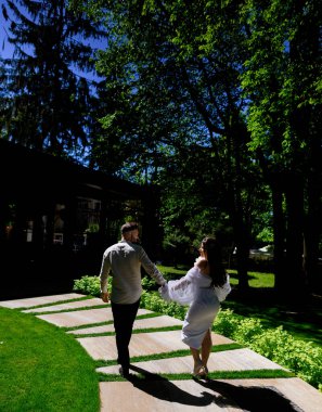 Yeni evli güzel beyaz çift, parlak güneş ışığında el ele yürür. Genel görünüm dikey fotoğraf