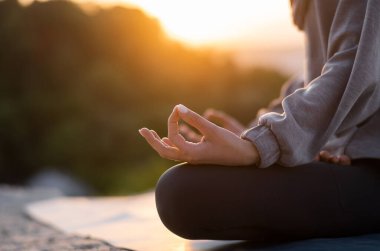 Gün batımında meditasyon yapan ve yoga yapan bir kızın eli. Kapat.