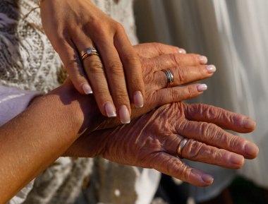 Güneş ışığının arka planında büyükanne kız ve torunun elleri 