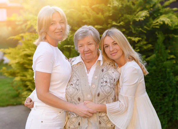 老祖母和孙女白种人的模样拥抱在夕阳下的花园 — 图库照片