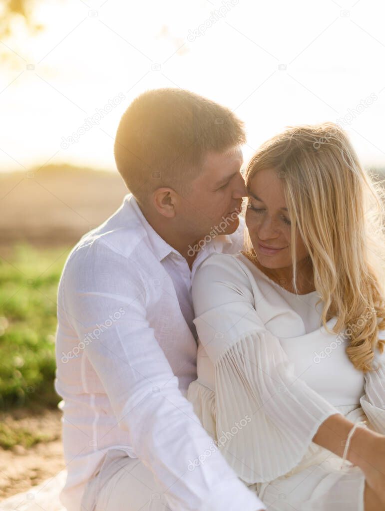 Portrait of a beautiful caucasian couple embracing on a background of sunset in the field
