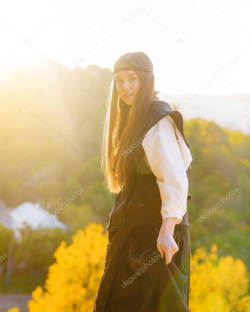 Beautiful young caucasian girl in Ukrainian traditional national dress at sunset on the mountain overlooking the landscape
