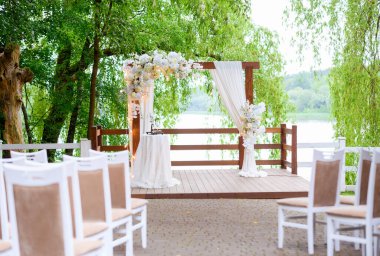 Ormandaki törenler için gölün arka planında güzel bir yaz düğünü kemeri.