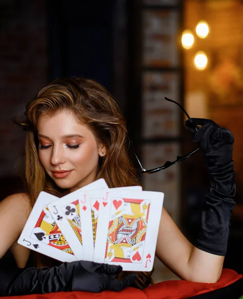 Portrait of a beautiful Caucasian girl posing with large playing cards in a restaurant