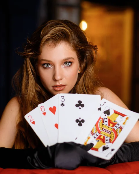 Close-up portrait of a beautiful Caucasian girl posing with large playing cards in a restaurant