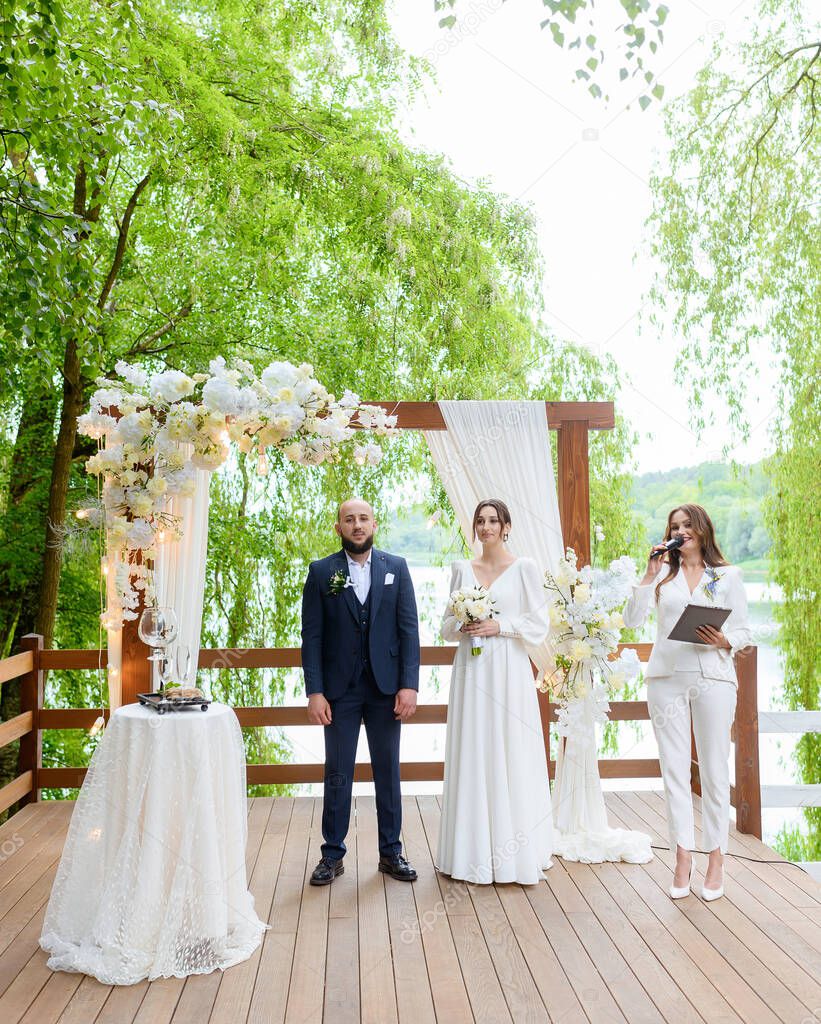 A beautiful couple of newlyweds make marriage promises against the background of the wedding arch ceremony in the forest