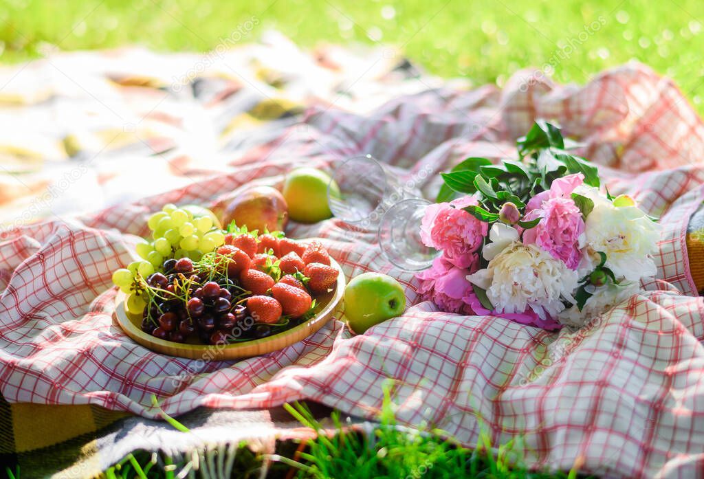 Strawberries on a plate on the background of a white blanket on a picnic in a green field with croissants
