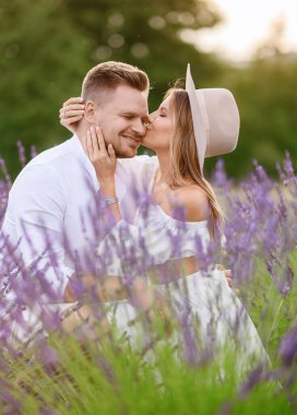 Gün batımında lavanta tarlasında sarılan açık renk elbiseli güzel bir çiftin portresi.