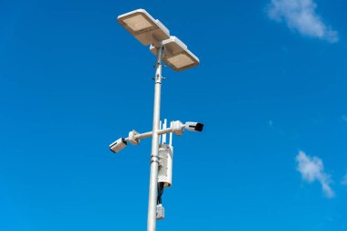 Mavi gökyüzü arka planlı mobese kamerası. Sokak direğindeki güvenlik kameralarının yakın çekimleri sokaktaki güvenliği sağlıyor..