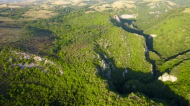 Aerial view of karst landscape, in Romania, with valleys and cliffs, at sunset