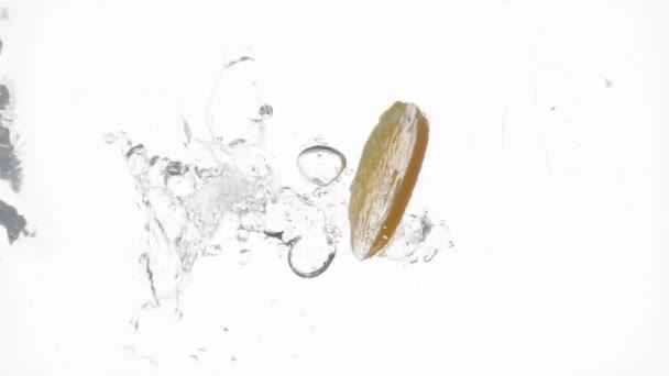 Slow Motion Close Orange Slice Falling Water Creating Bubbles White — Stockvideo