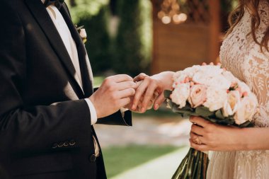 Damat (adam) düğünde geline (kız) sol elinin parmağına yüzük takar. El ele. Düğün için. Ziyaret töreni. Gelinlik. Gelin ve damat.