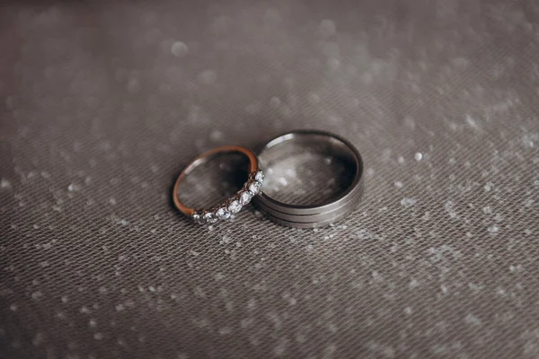 The wedding rings of the bride and groom in white gold lie on a shiny white veil. Wedding. Engagement.