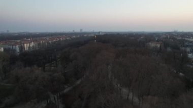 Amazing fly by Angel of Peace in Munich, Germany with the view on the city center, Frauenkirche and Marienplatz on a golden sunrise. Aerial golden hour Friedensengel.
