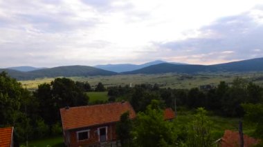Dağlardaki küçük bir köyün altın bir günbatımında havadan çekilmiş görüntüsü.