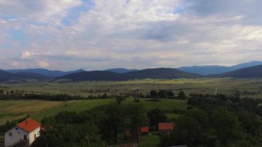 Dağlardaki küçük bir köyün altın bir günbatımında havadan çekilmiş görüntüsü.