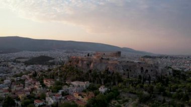 Atina, Yunanistan 'da hava manzarası, yazın gün doğumu. Altın güneş ışınlarının insansız hava aracı atışı zengin Parthenon 'u vurdu. Yunan başkentinin panorama 'sı, sakin sabah deniz arka planında üstgeçit.