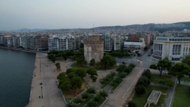Güneş doğarken Selanik Beyaz Kulesi 'nin havadan görünüşü. Sabahın yumuşak ışıklarıyla drone atışı. Yunanistan 'ın denizdeki büyük şehri. Rıhtımdaki tahta yolun yanındaki tarihi anıt..