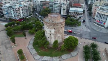 Güneş doğarken Selanik Beyaz Kulesi 'nin havadan görünüşü. Sabahın yumuşak ışıklarıyla drone atışı. Yunanistan 'ın denizdeki büyük şehri. Rıhtımdaki tahta yolun yanındaki tarihi anıt..