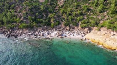 Ege Denizi 'ndeki Yunan Thassos Adası' ndaki turkuaz sularla dolu güzel ve gizli sahilin havadan görünüşü. Bir yaz günü taşlı ve kumlu berrak mavi suyun insansız hava aracı görüntüleri.