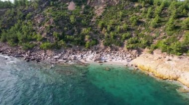 Ege Denizi 'ndeki Yunan Thassos Adası' ndaki turkuaz sularla dolu güzel ve gizli sahilin havadan görünüşü. Bir yaz günü taşlı ve kumlu berrak mavi suyun insansız hava aracı görüntüleri.