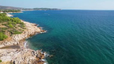 Ege Denizi 'ndeki Yunan Thassos Adası' ndaki turkuaz sularla dolu güzel ve gizli sahilin havadan görünüşü. Bir yaz günü taşlı ve kumlu berrak mavi suyun insansız hava aracı görüntüleri.