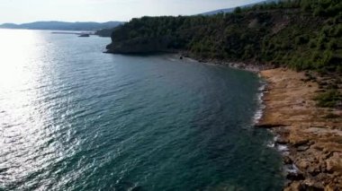 Ege Denizi 'ndeki Yunan Thassos Adası' ndaki turkuaz sularla dolu güzel ve gizli sahilin havadan görünüşü. Bir yaz günü taşlı ve kumlu berrak mavi suyun insansız hava aracı görüntüleri.