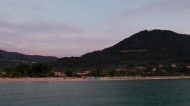 Ege Denizi 'ndeki Yunan adası Thassos' ta turkuaz sularla birlikte güzel Altın Sahilde güneşin doğuşunu gösteren hava manzarası. Bir yaz sabahında altın suyun insansız hava aracı görüntüleri. Altın saat